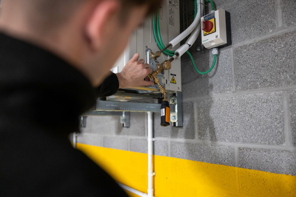 Technicus voert onderhoud uit aan HVAC-systeem in kelder.