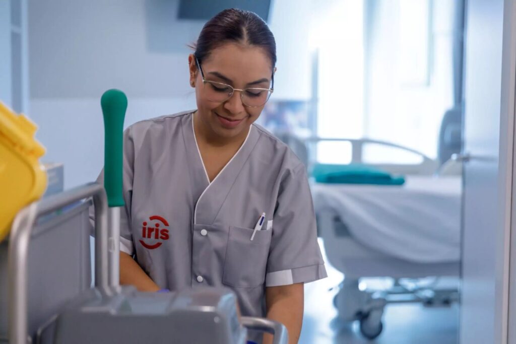 Female cleaner in hospital uniform with cleaning cart.